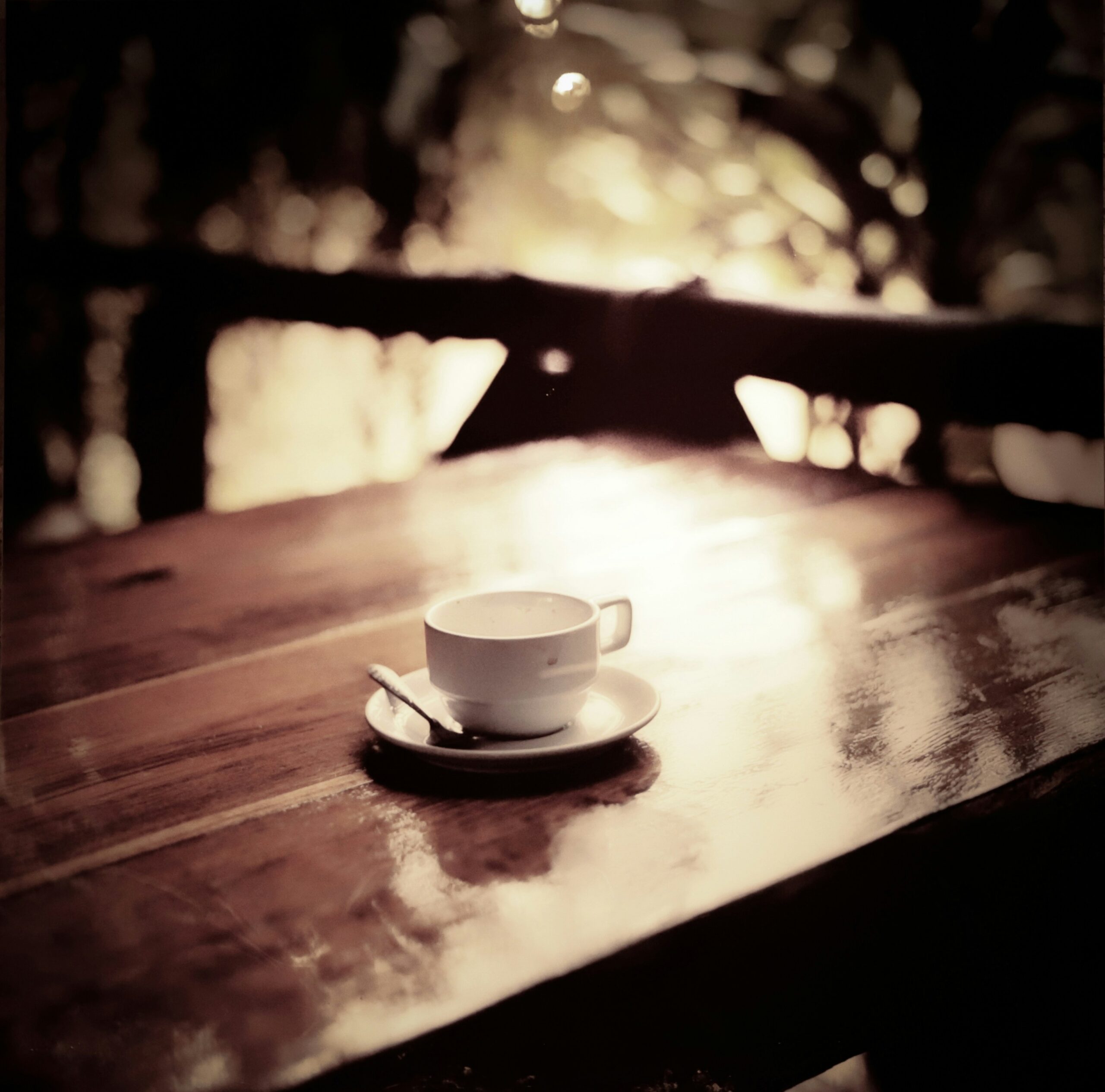 Warm and inviting photo of a cup of coffee with coffee beans on a wooden table giving a cozy vibe