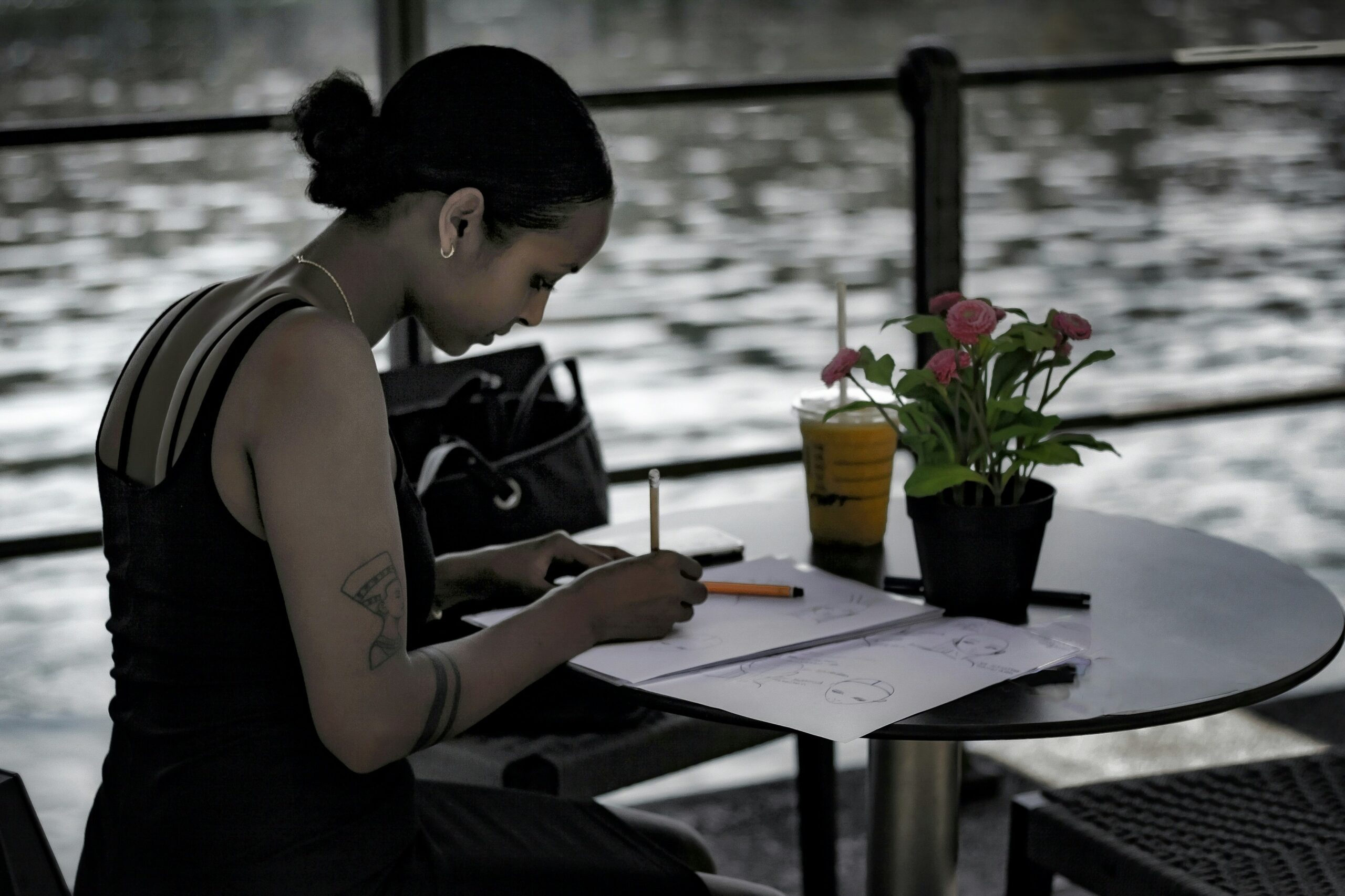Top down view of a woman hands writing in a journal with a cup of coffee beside her on a wooden desk