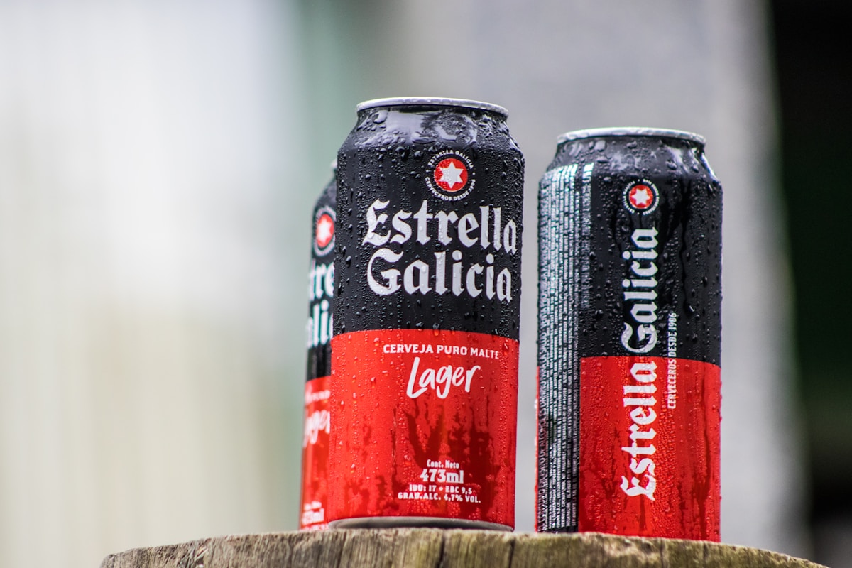 two cans of beer sitting on top of a wooden stump