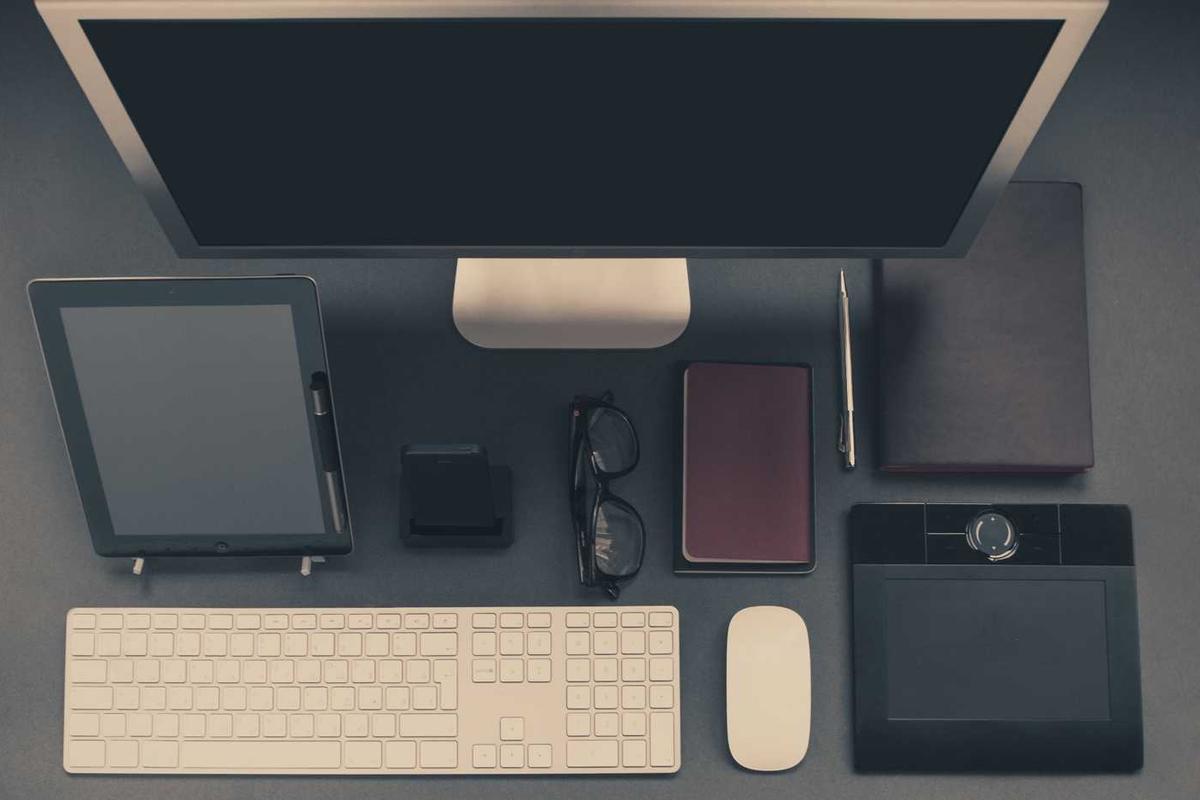 Overhead view of desk with tech and notebooks.