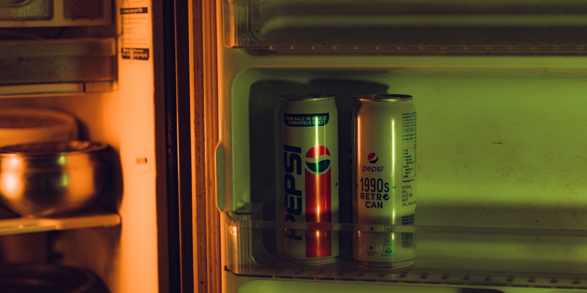 two cans of soda are in a refrigerator