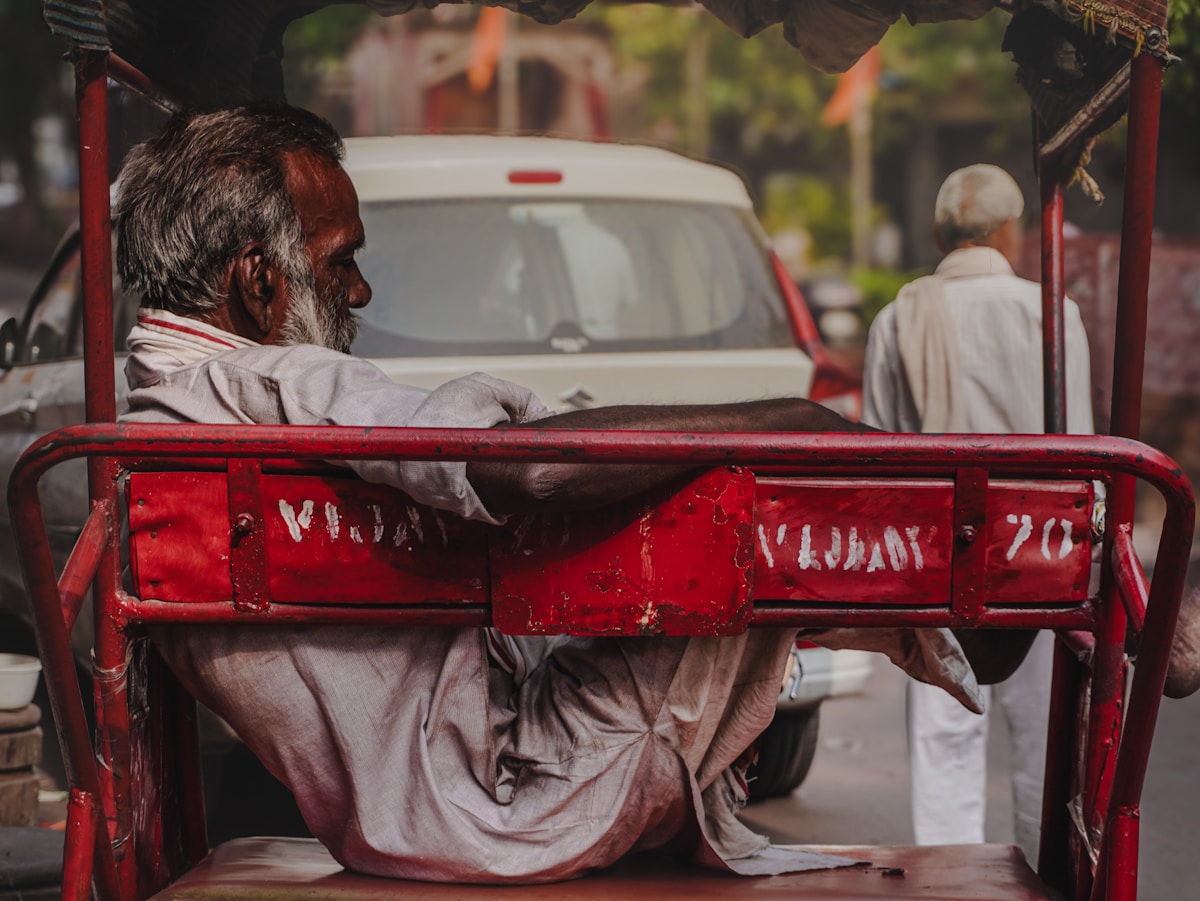 Man sitting in a red rickshaw on a street