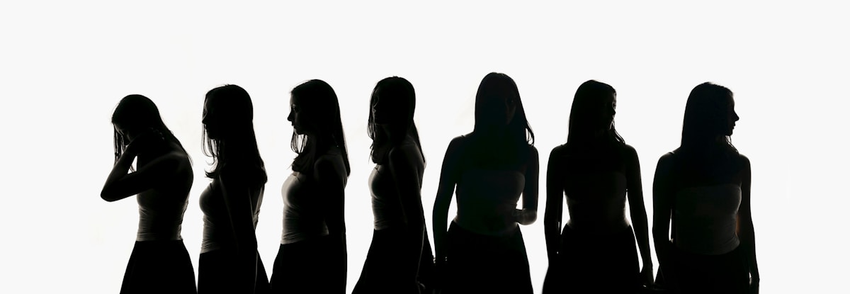 Silhouettes of seven women against a white background.