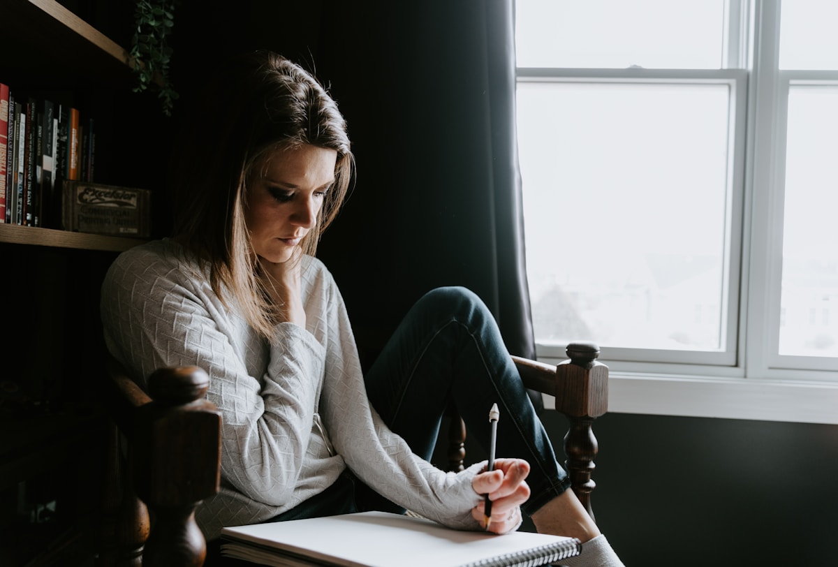 Woman sitting in chair writing in notebook