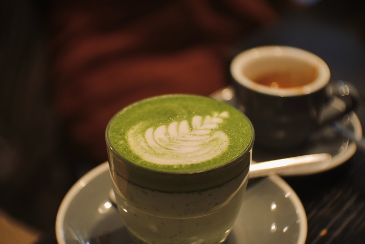 a cup of green tea with a leaf on it